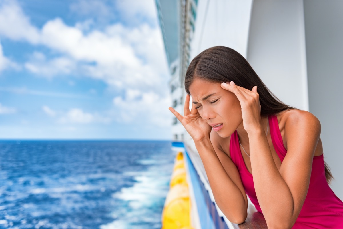 woman leans over cruise ship balcony seasick