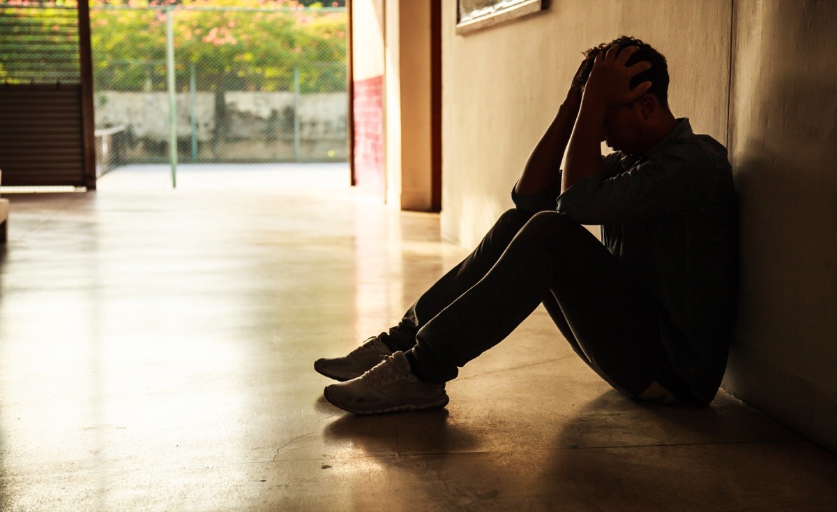 man sitting on the floor holding head in hands