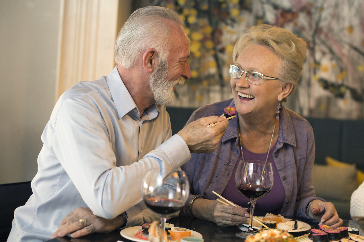 Senior couple in a restaurant, eating sushi.