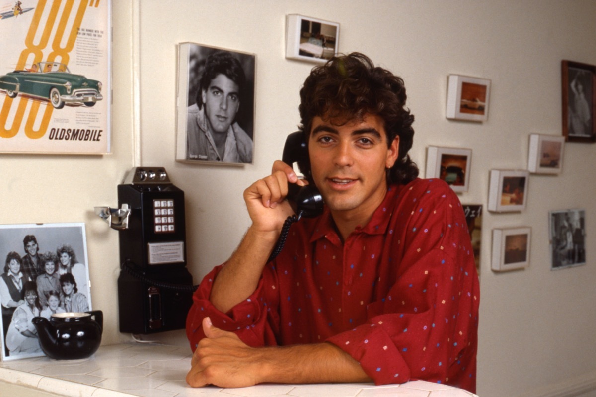 George Clooney siting at a table and talking on the phone