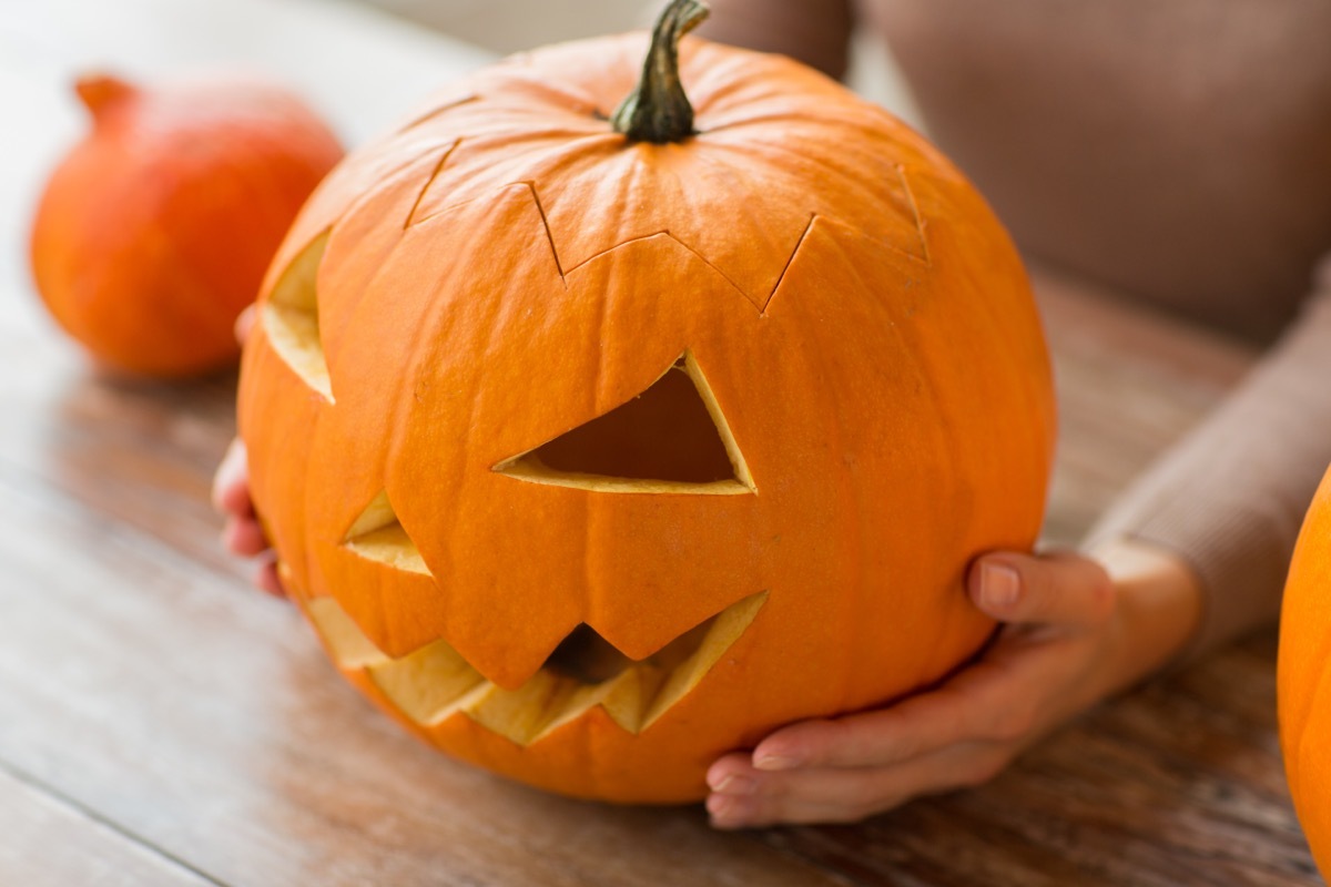 hands holding jack-o-lantern on table indoors