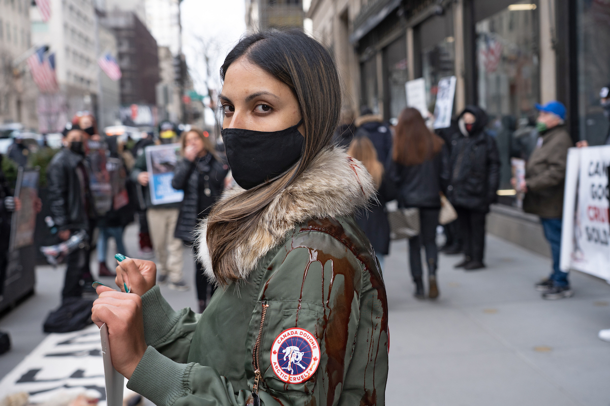 A protester wearing Canada Goose coat cover with blood stands in a pool of blood during a Canada Goose protest in front of Saks Fifth Avenue flagship Store.