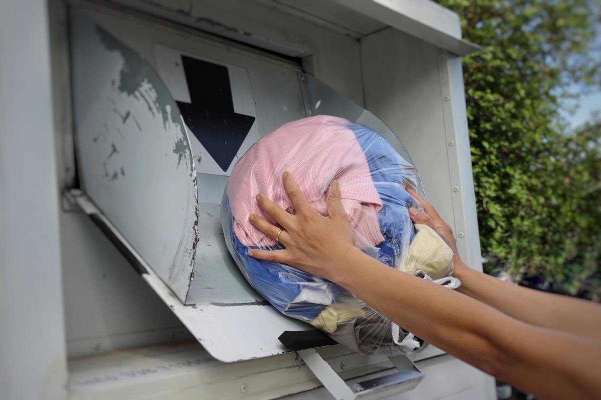 putting clothes in donation bin