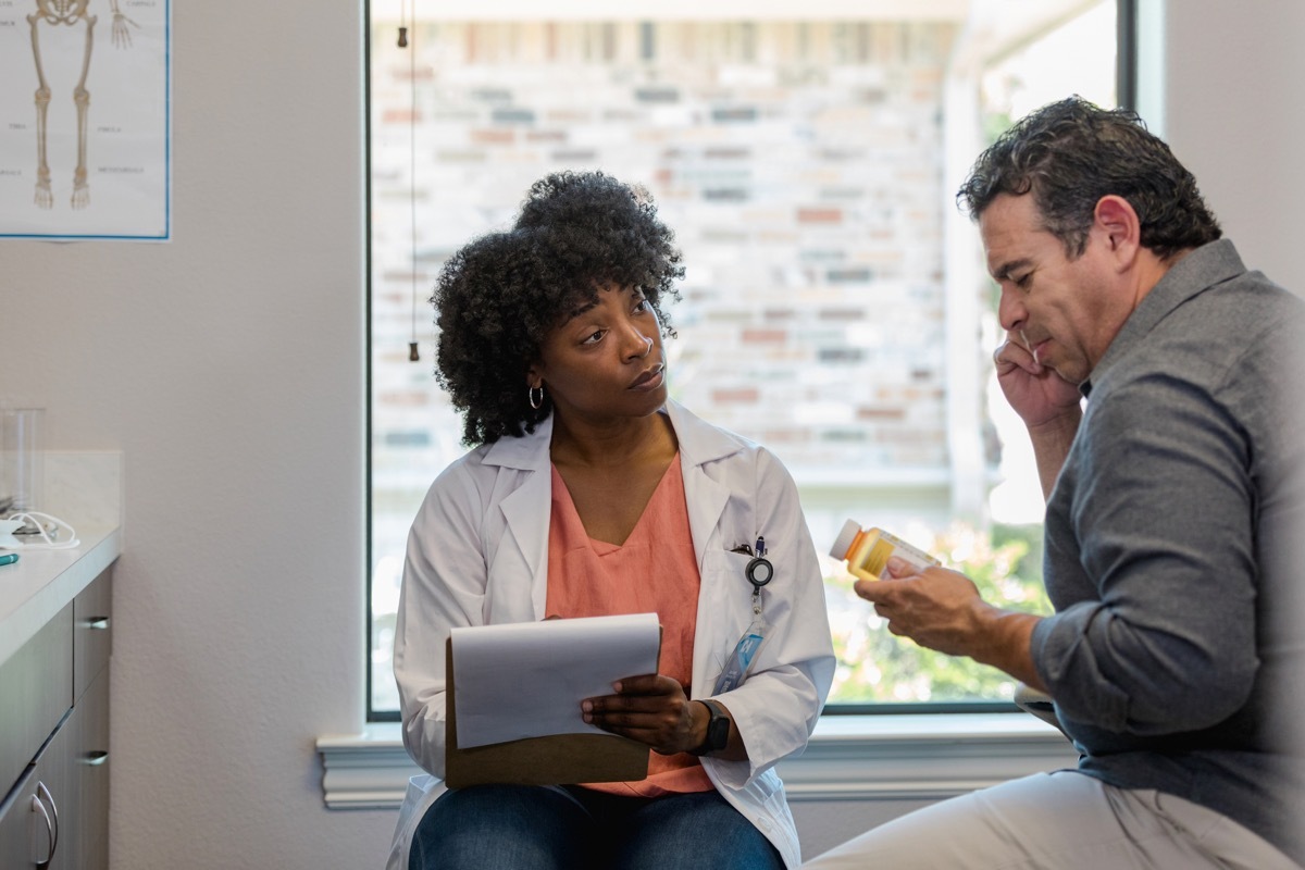 The mid adult doctor listens carefully as the mature adult male patient describes the side effects from the new medication.