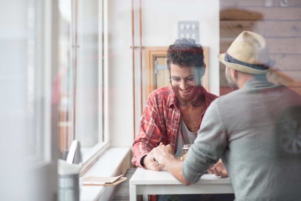 two men holding hands at a restaurant