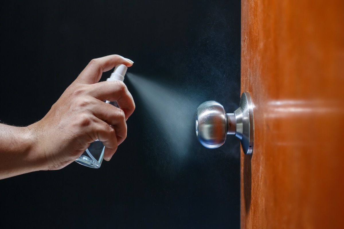 Cleaning door knob with alcohol spray for Covid-19 (Coronavirus) prevention.