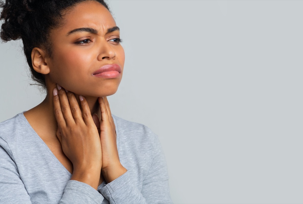 woman suffering from pain in throat, touching her neck, empty space.