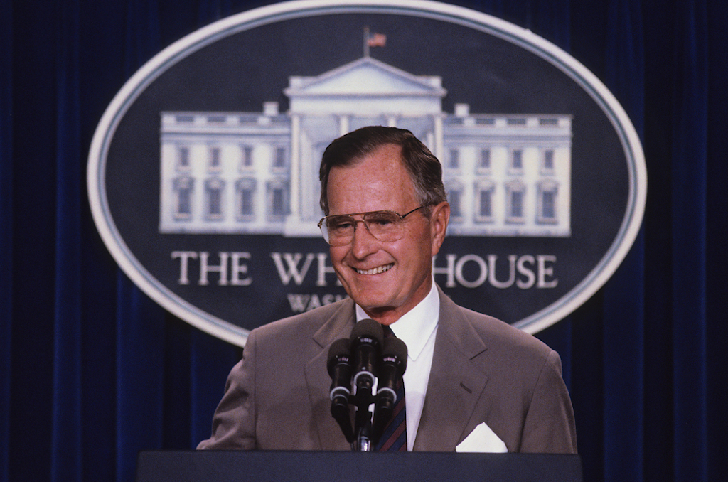 george h.w. bush tands at the podium as he responds to reporters questions during a news conference in the press briefing room at the White House in 1990.