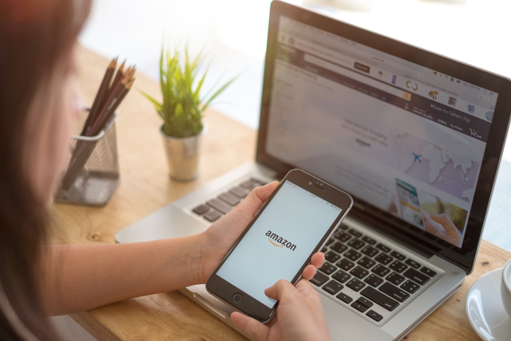 A woman shopping on Amazon using a laptop and phone