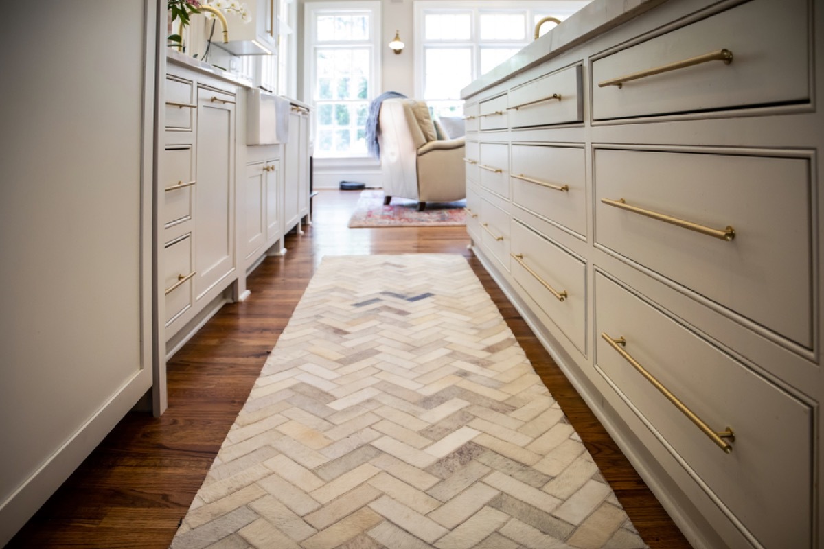 white brick patterned runner rug between two rows of lower kitchen cabinets