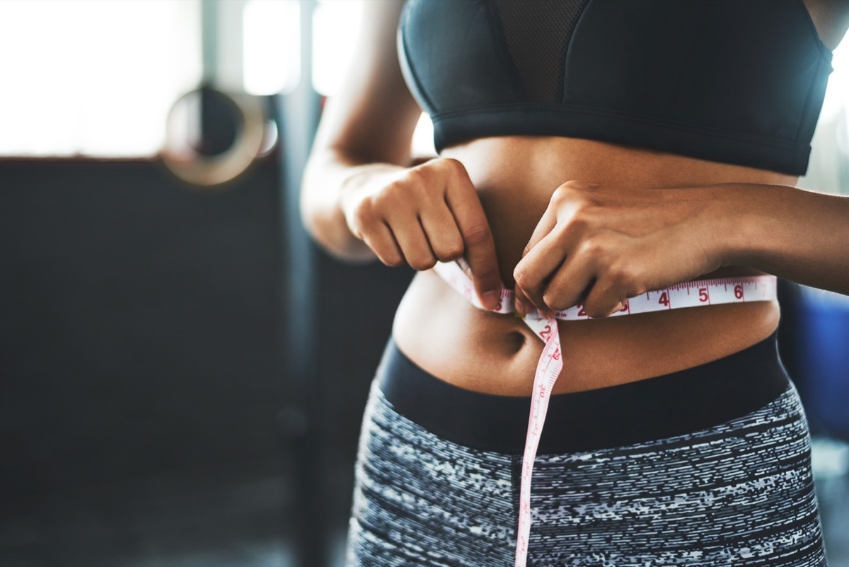 close up of woman measuring her waist at the gym