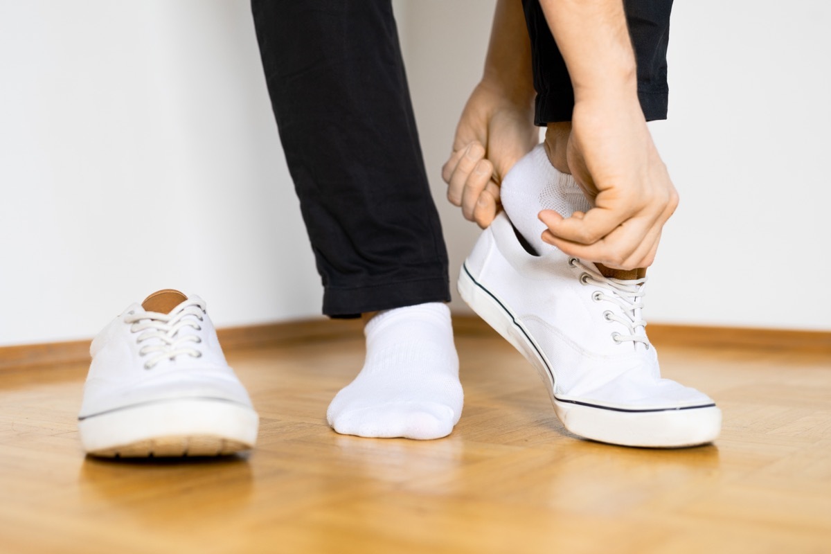 put on white sneaker shoes on wooden floor and white background