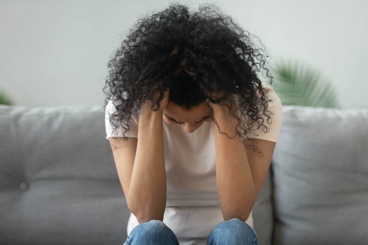 woman hold head in hands suffer from grief problem, depressed lonely upset african girl crying alone on sofa at home