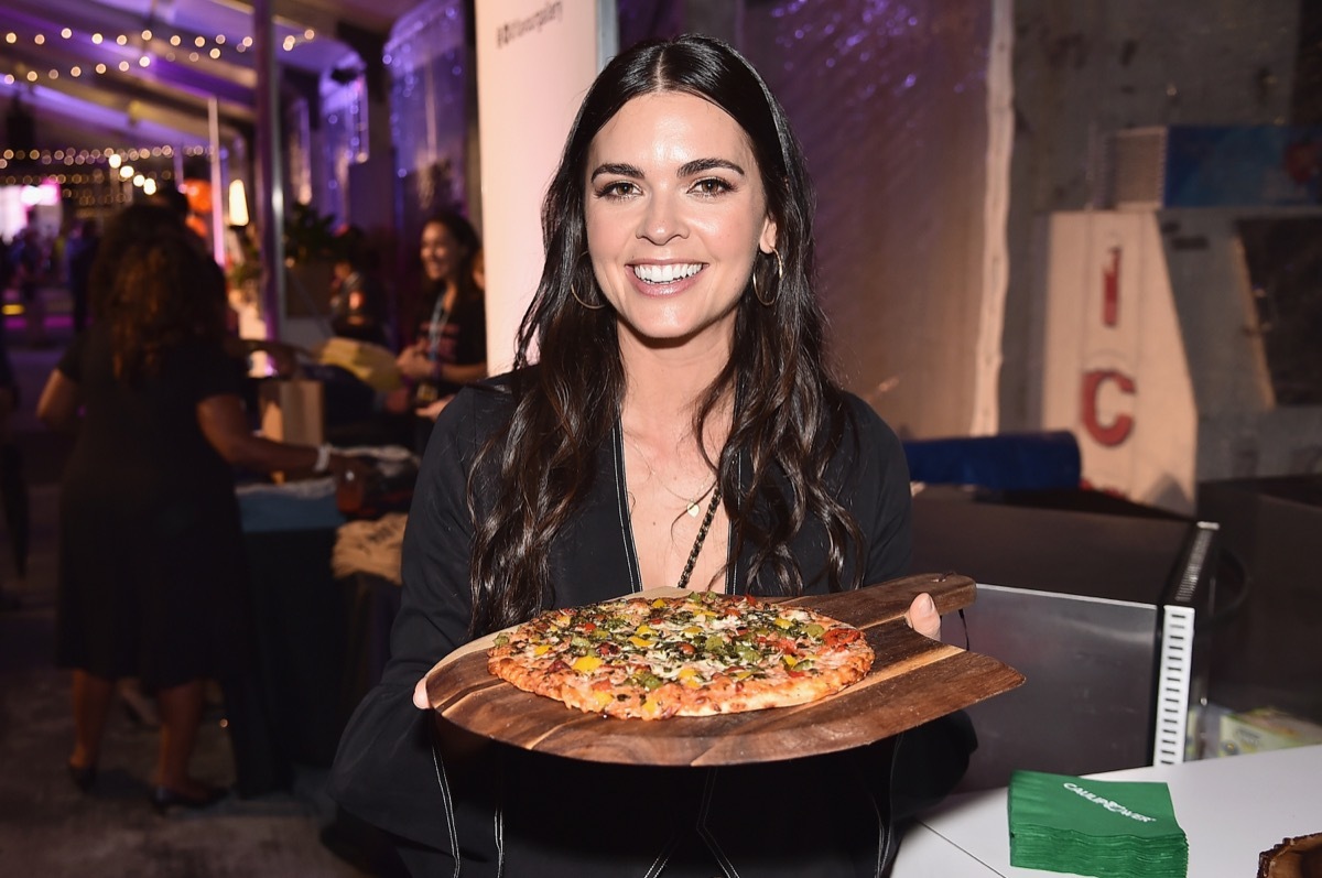 katie lee biegel holding a pan with pizza on it