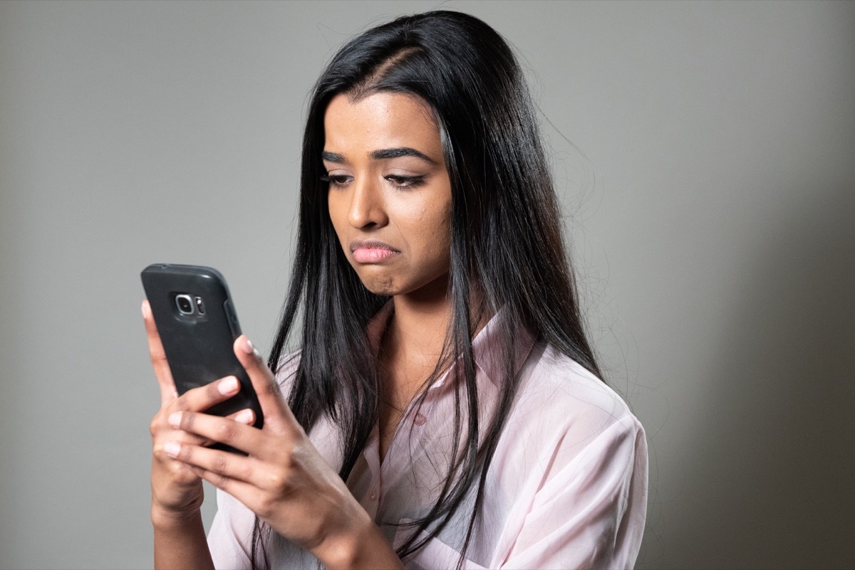 unimpressed woman looking at her phone