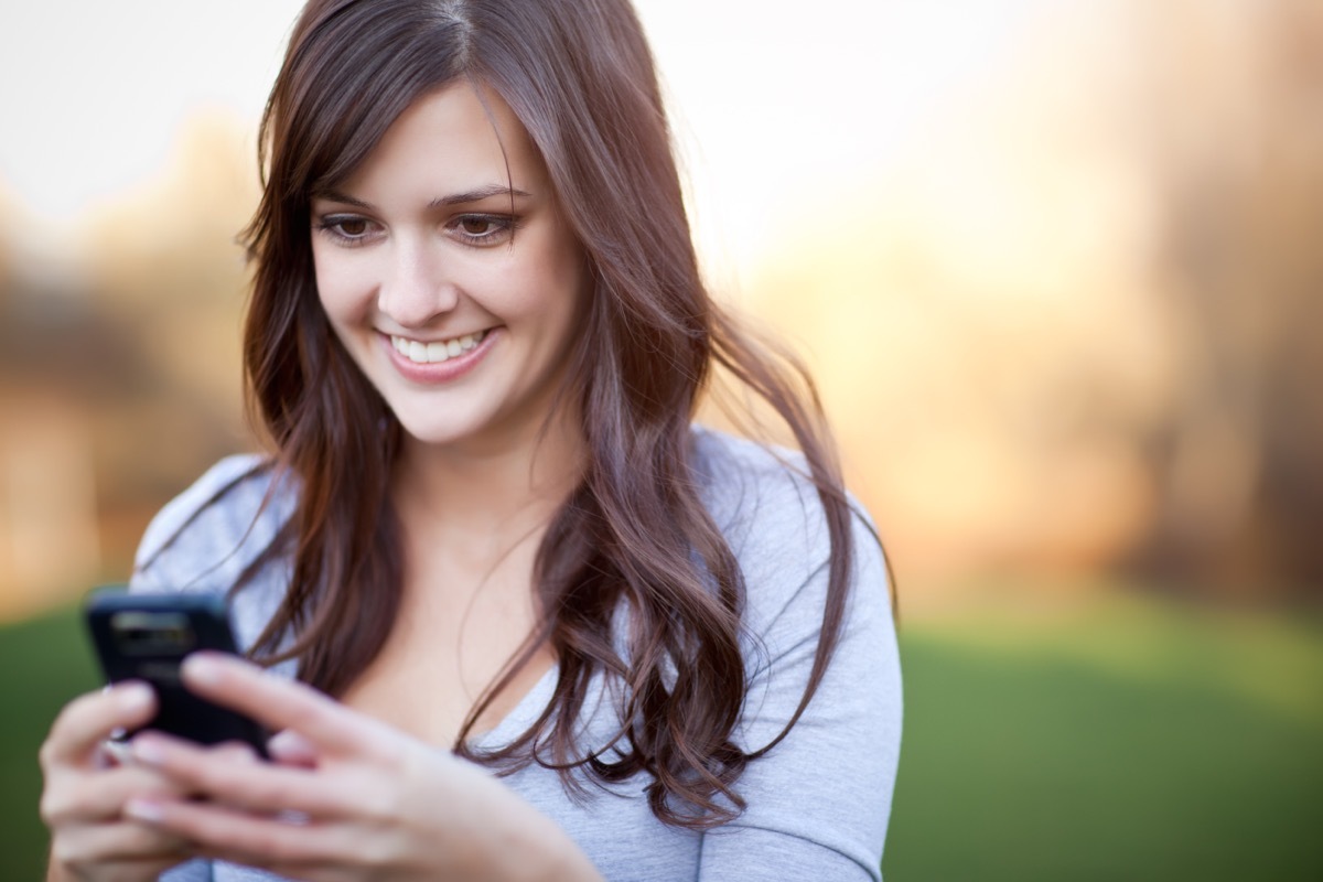 woman texting a friend and smiling