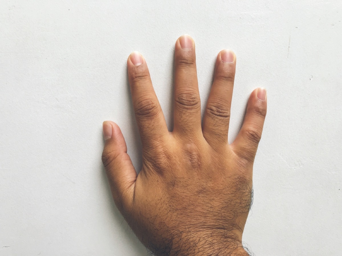 man's hand touching wall, signs your home is falling apart