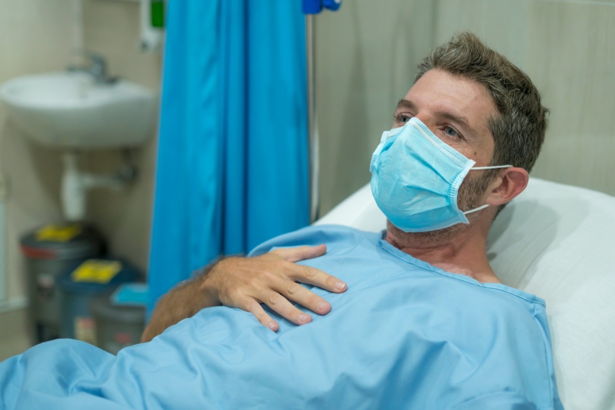 adult male in face mask receiving treatment at hospital suffering respiratory disease lying on bed