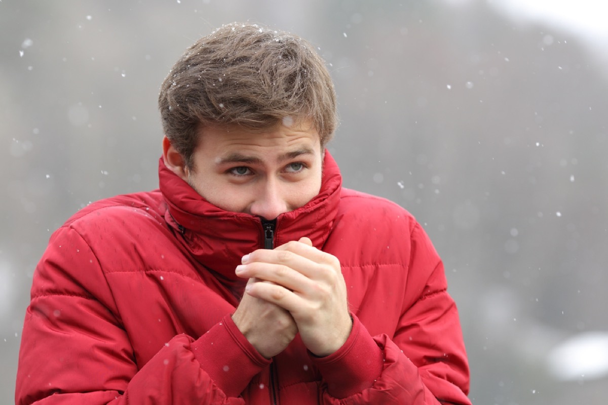 white man in snow with jacket pulled up over his face