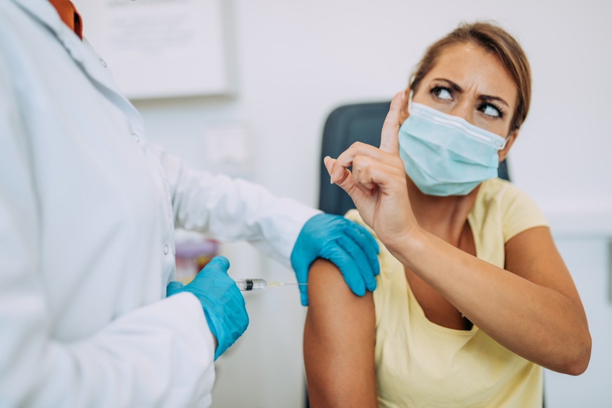 Female doctor or nurse trying to give shot or vaccine against virus to a scared patient.