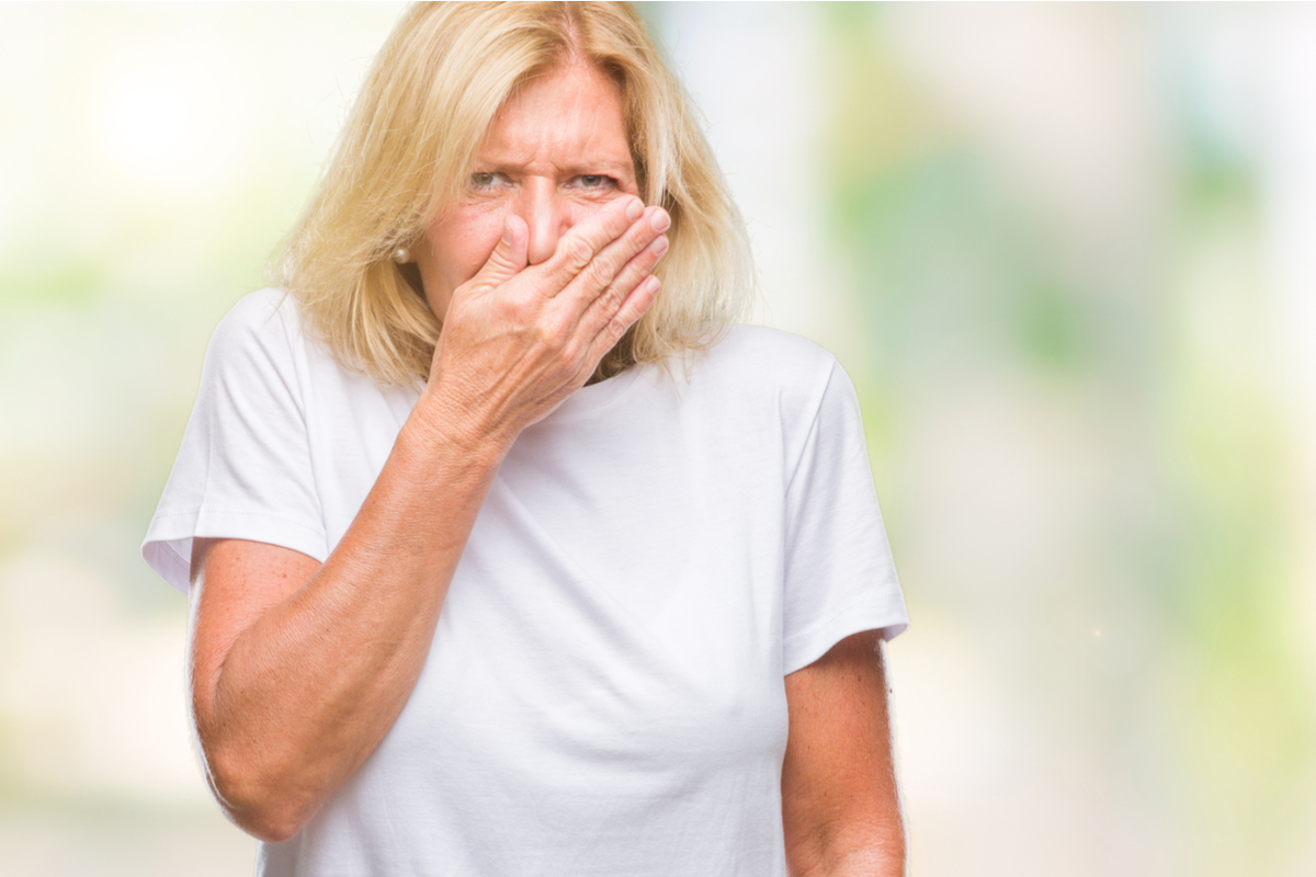 older white woman covering her mouth and holding her nose