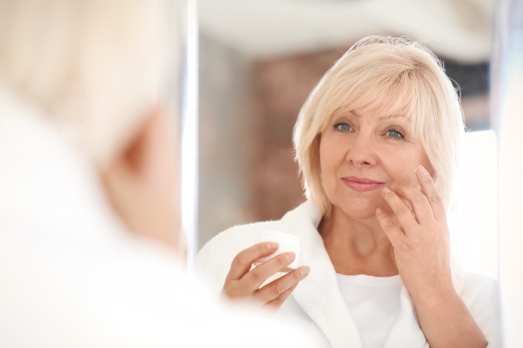 middle aged woman looking in a mirror, makeup for older women