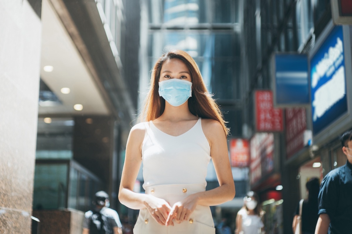 Woman with protective face mask commuting in downtown city street to protect and prevent from the spread of viruses in the city