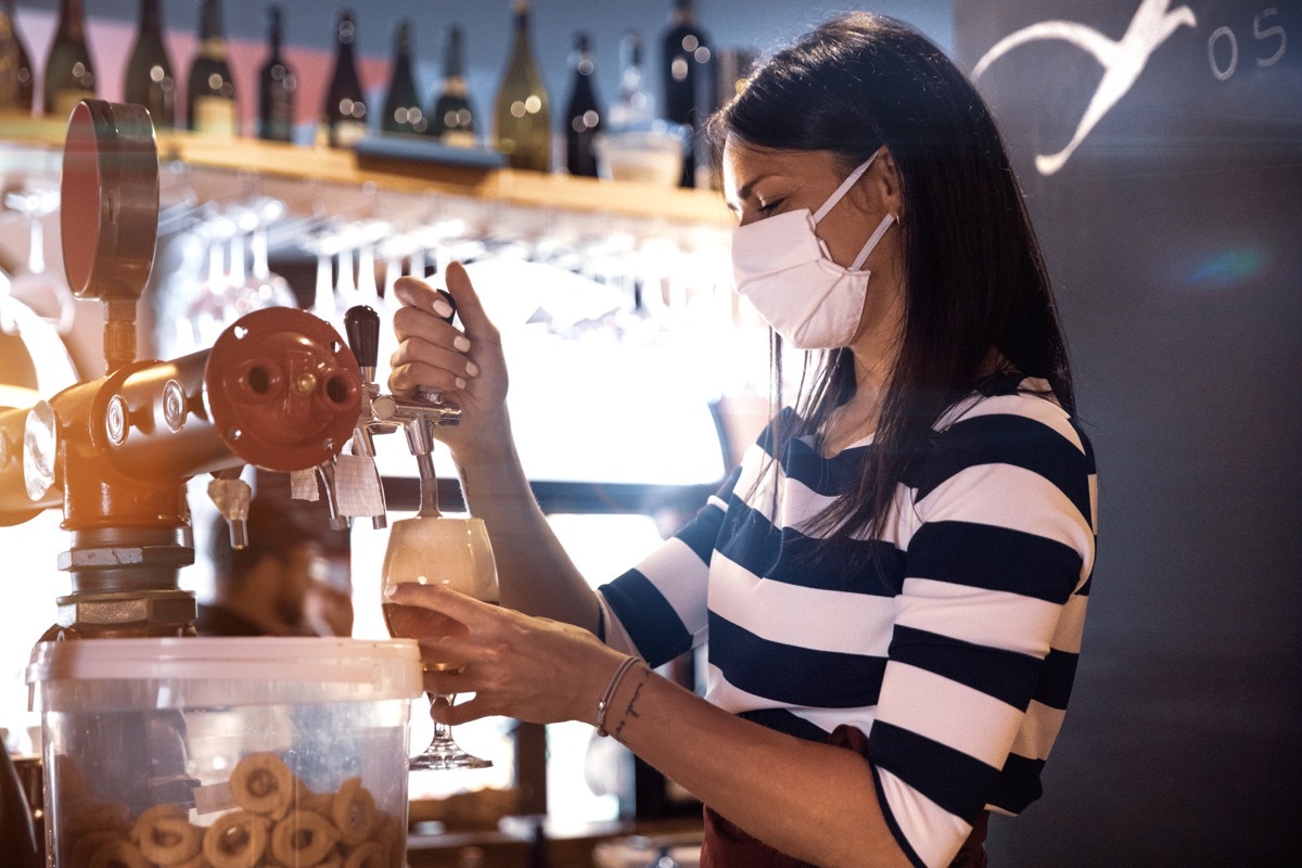 Bartender serves a fresh beer in a pub