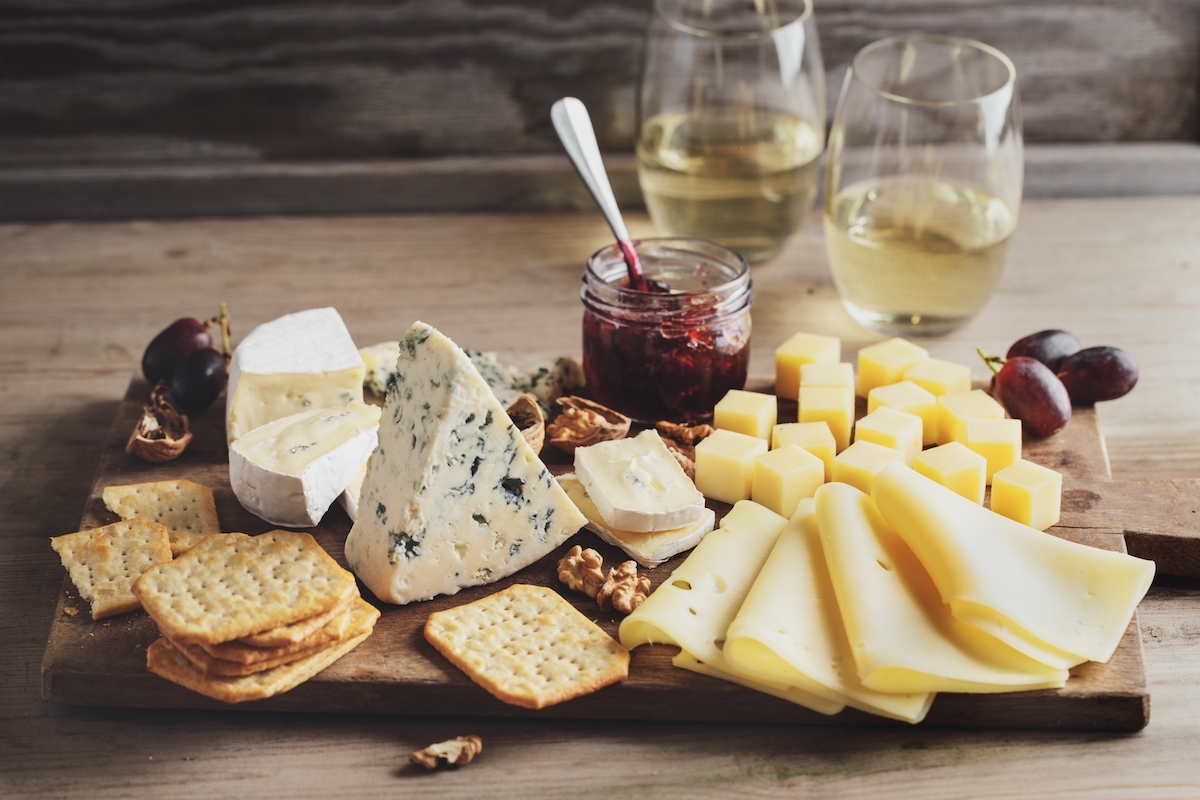 Cheese plate with different arts of cheese grape and nuts served on wooden board.