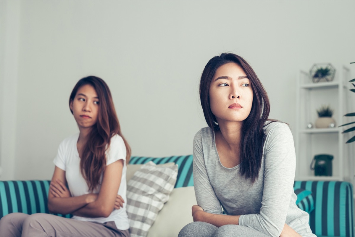 Young Asian lesbian couple argue and turn their back to each other in the bedroom