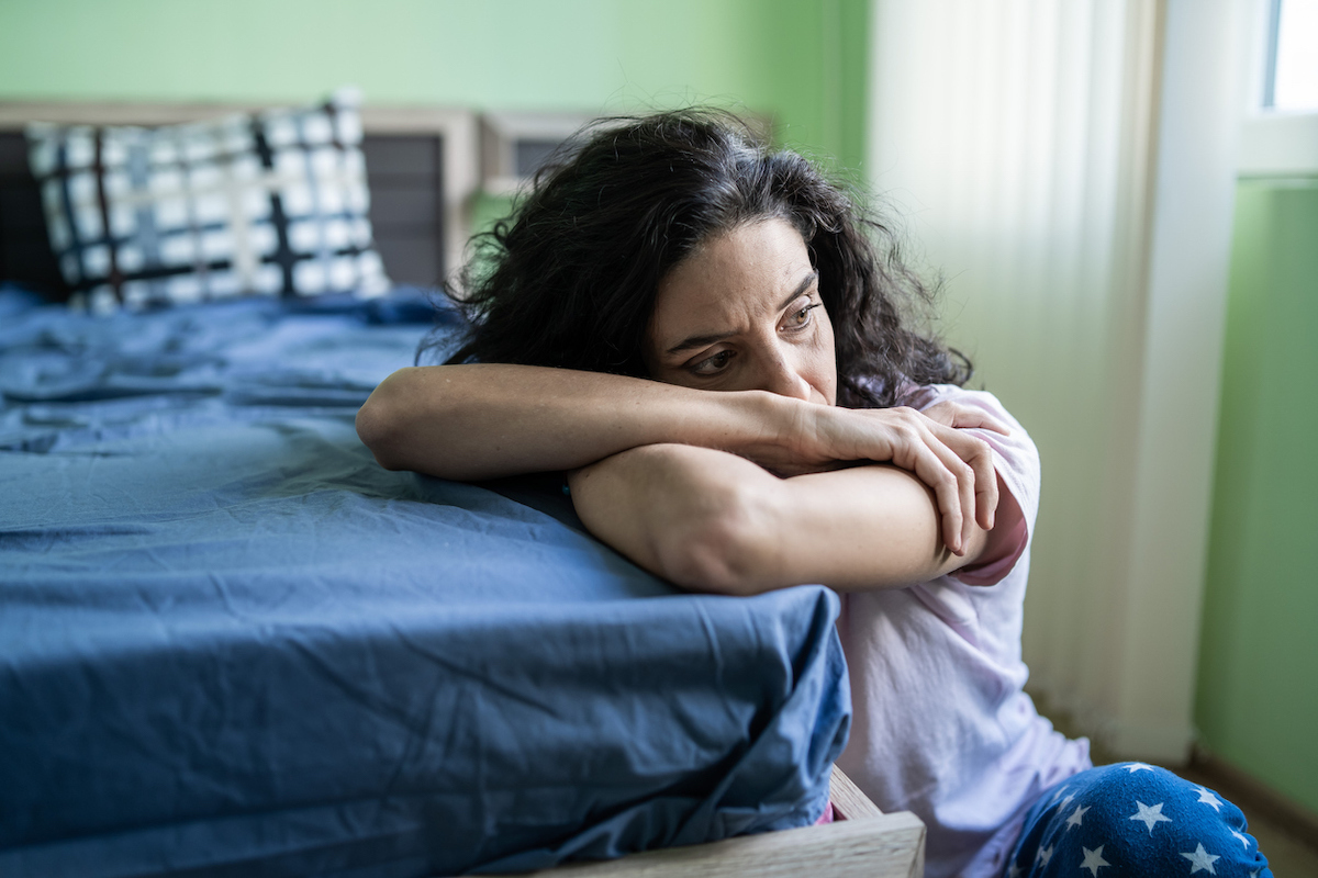 Mid adult woman sitting home alone, worried