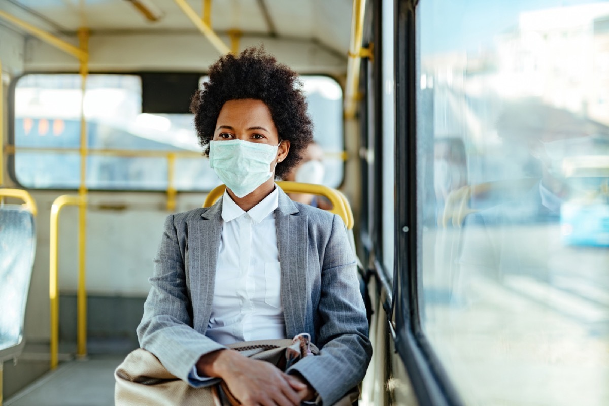 young black woman with a face mask on a bus