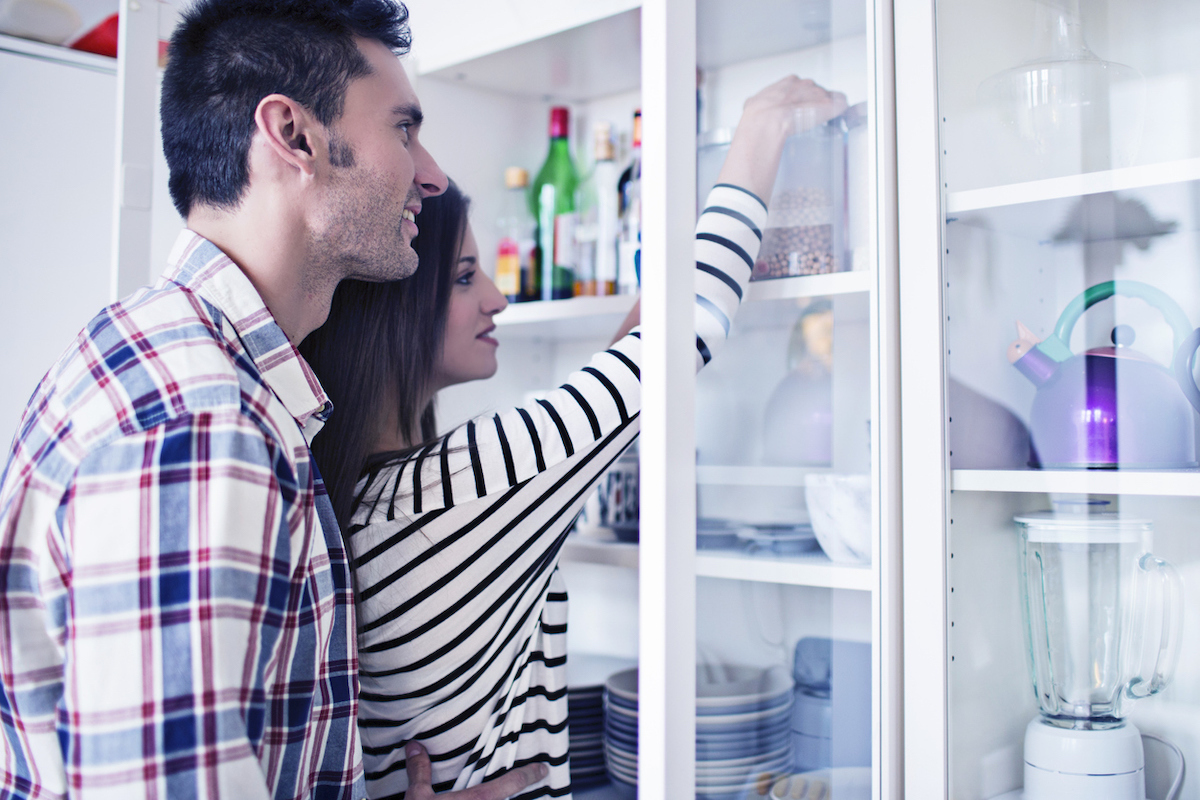 Young couple tidying up the kitchen cabinets