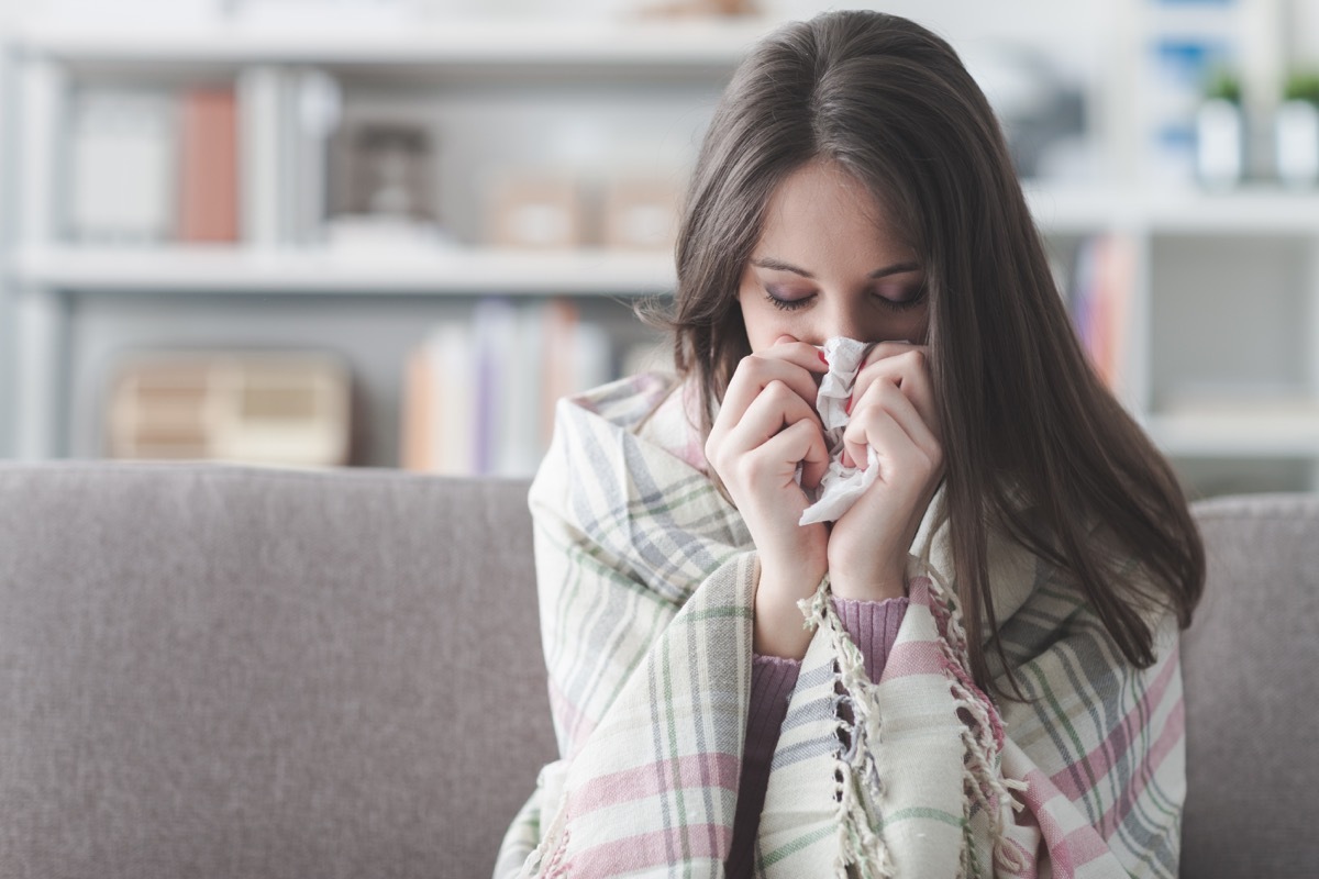 woman blowing her nose on the couch