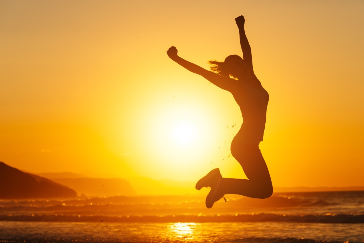 woman jumping into air on beach at sunset because she decided to delete instagram