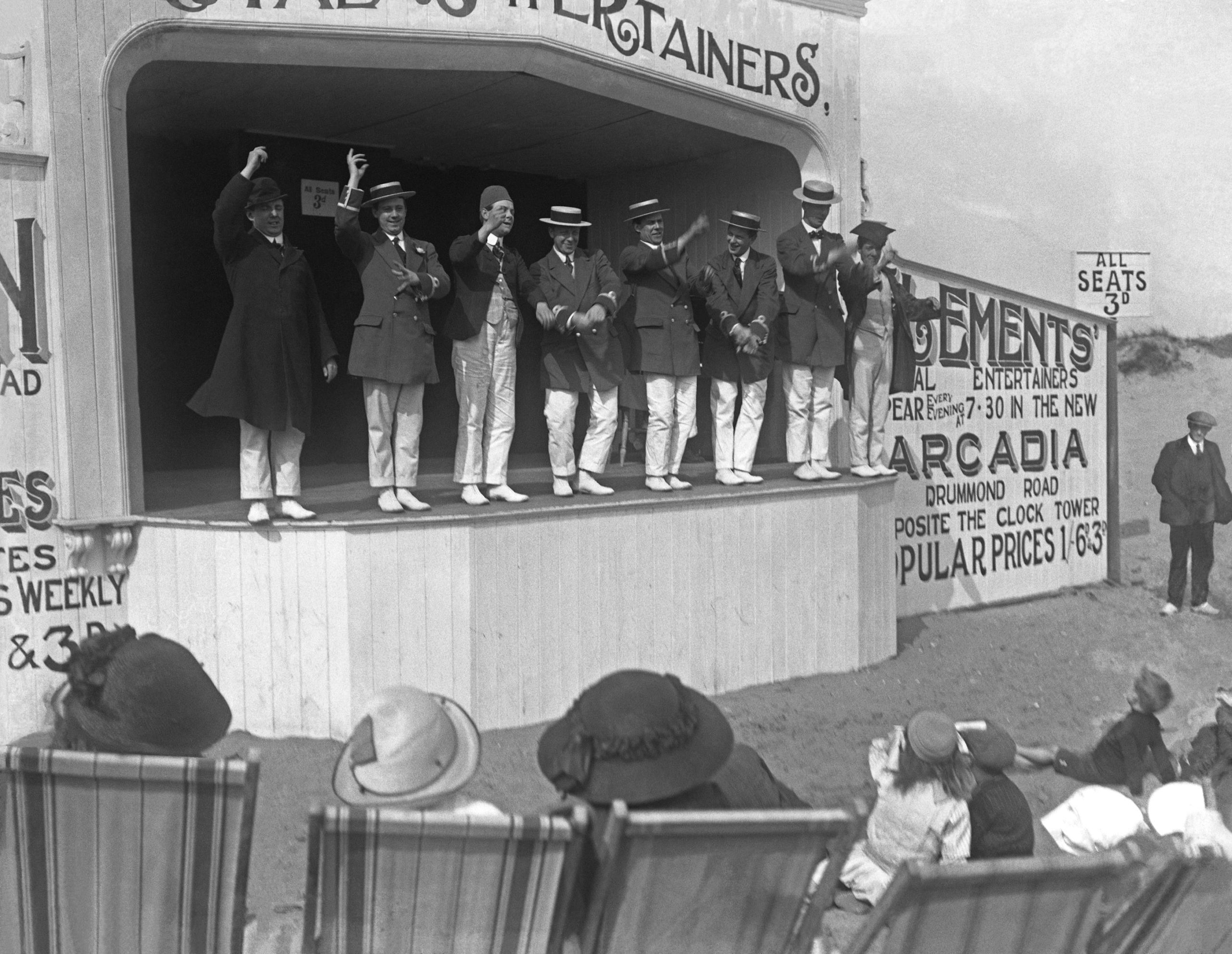 a group of performers host a stage show at the beach in the 1920s