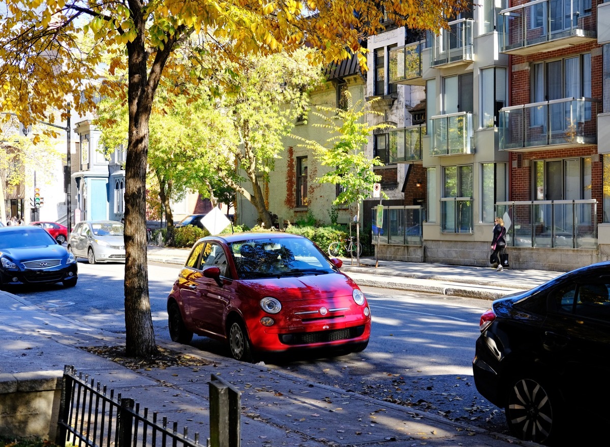 red car parked on shaded tree road