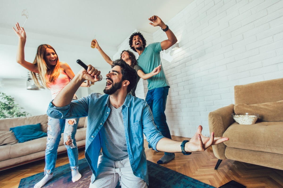 Group of friends playing karaoke at home.