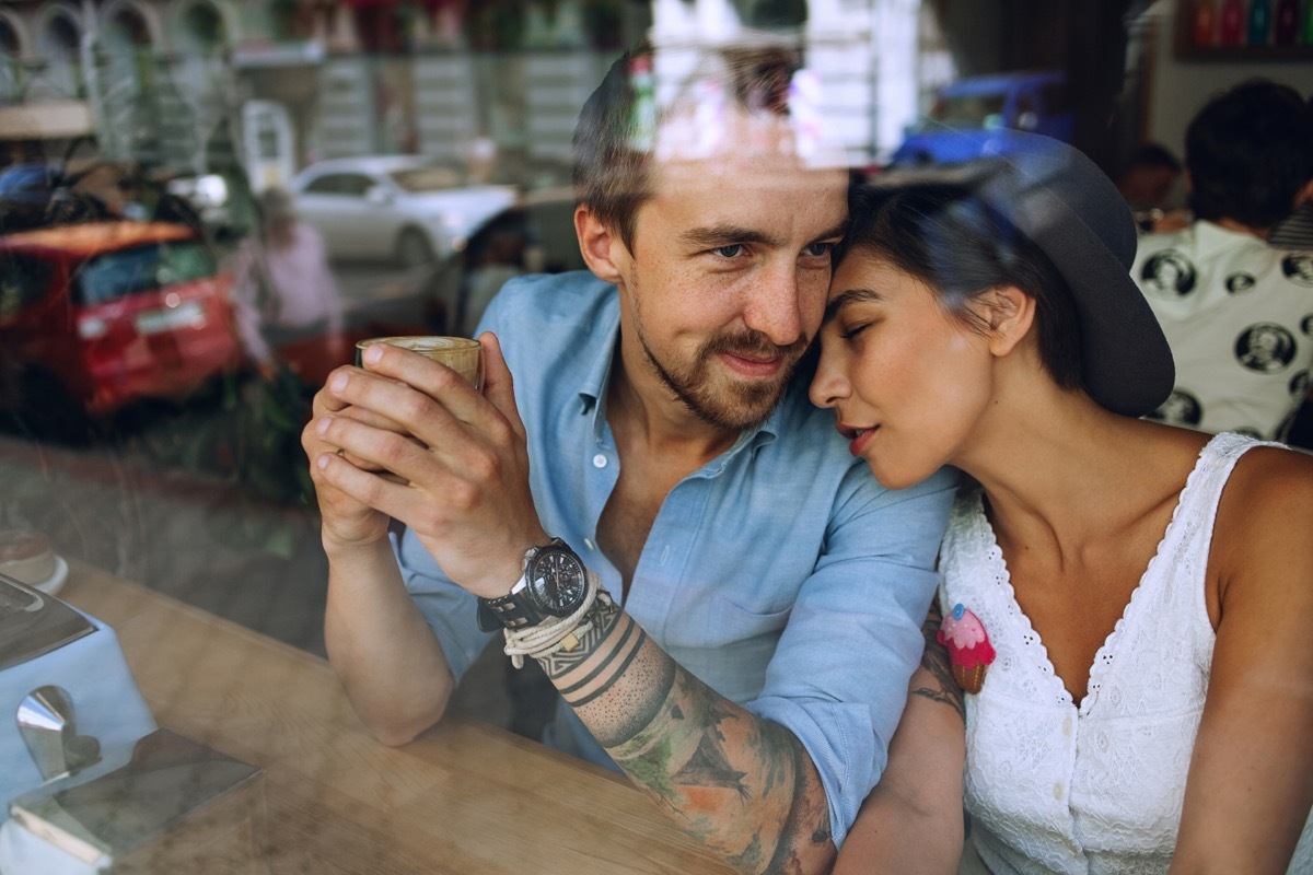 man and woman snuggling behind the window at a cafe