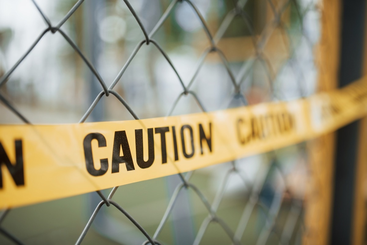 Do not enter. Yellow caution tape on the metal fence at daytime. Crime scene.