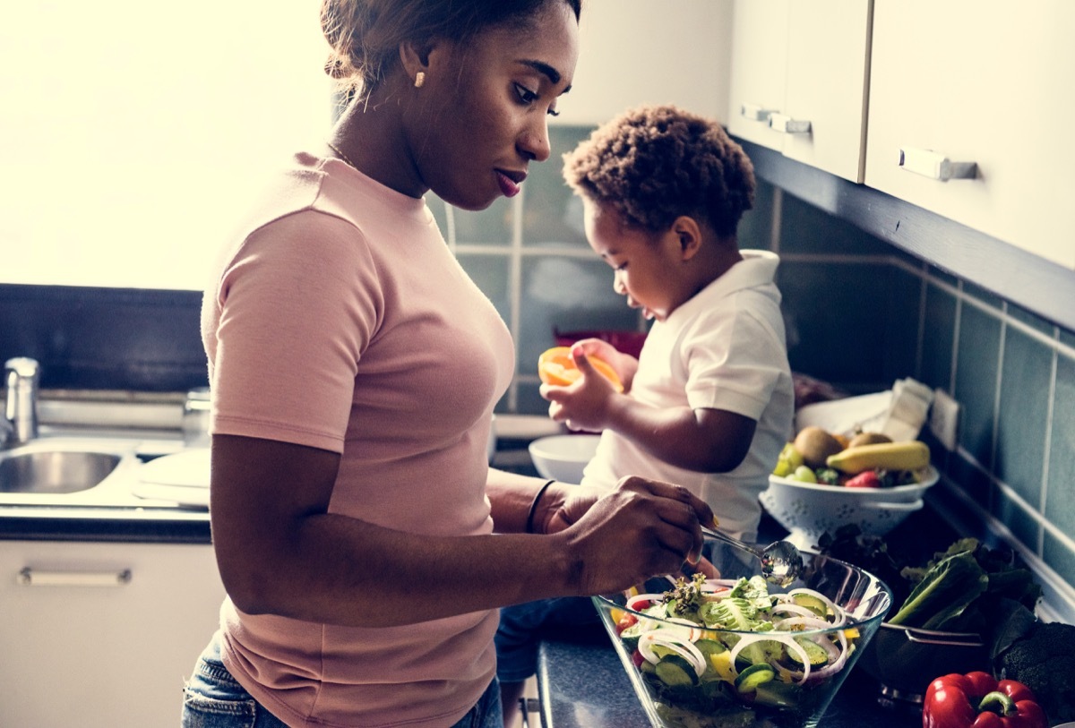 Mom cooking in the kitchen with her baby next to her on the counter