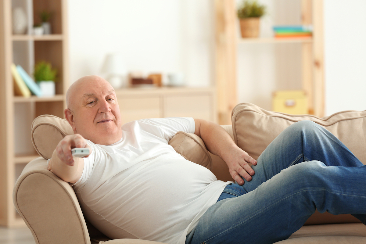 Out of shape older white man watching TV