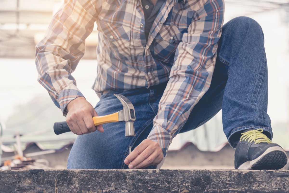 man holding a hammer to nail concrete floor