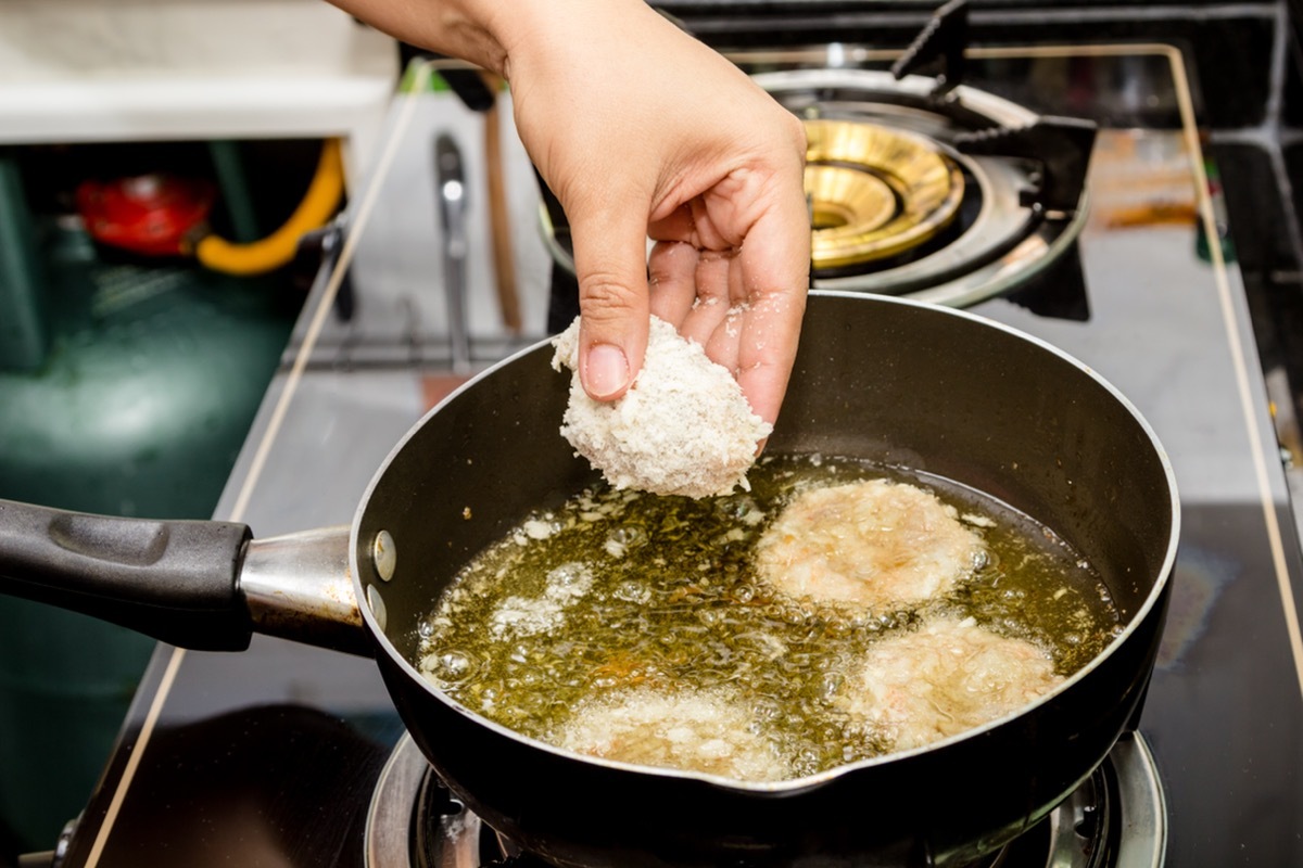 Hand Placing Meat in Pan to be Fried