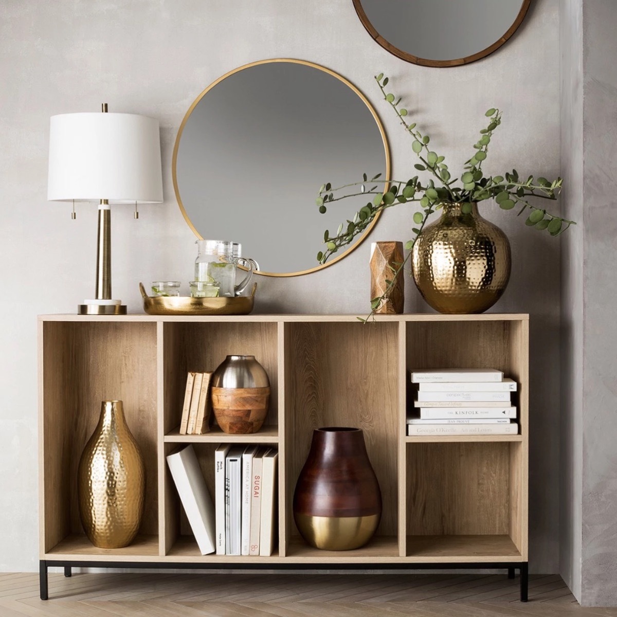 round gold mirror over bookcase