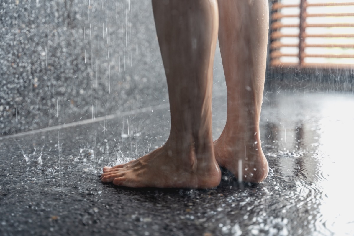 Legs of the girl standing under the shower under the stream of water, health beauty and hygiene concept.