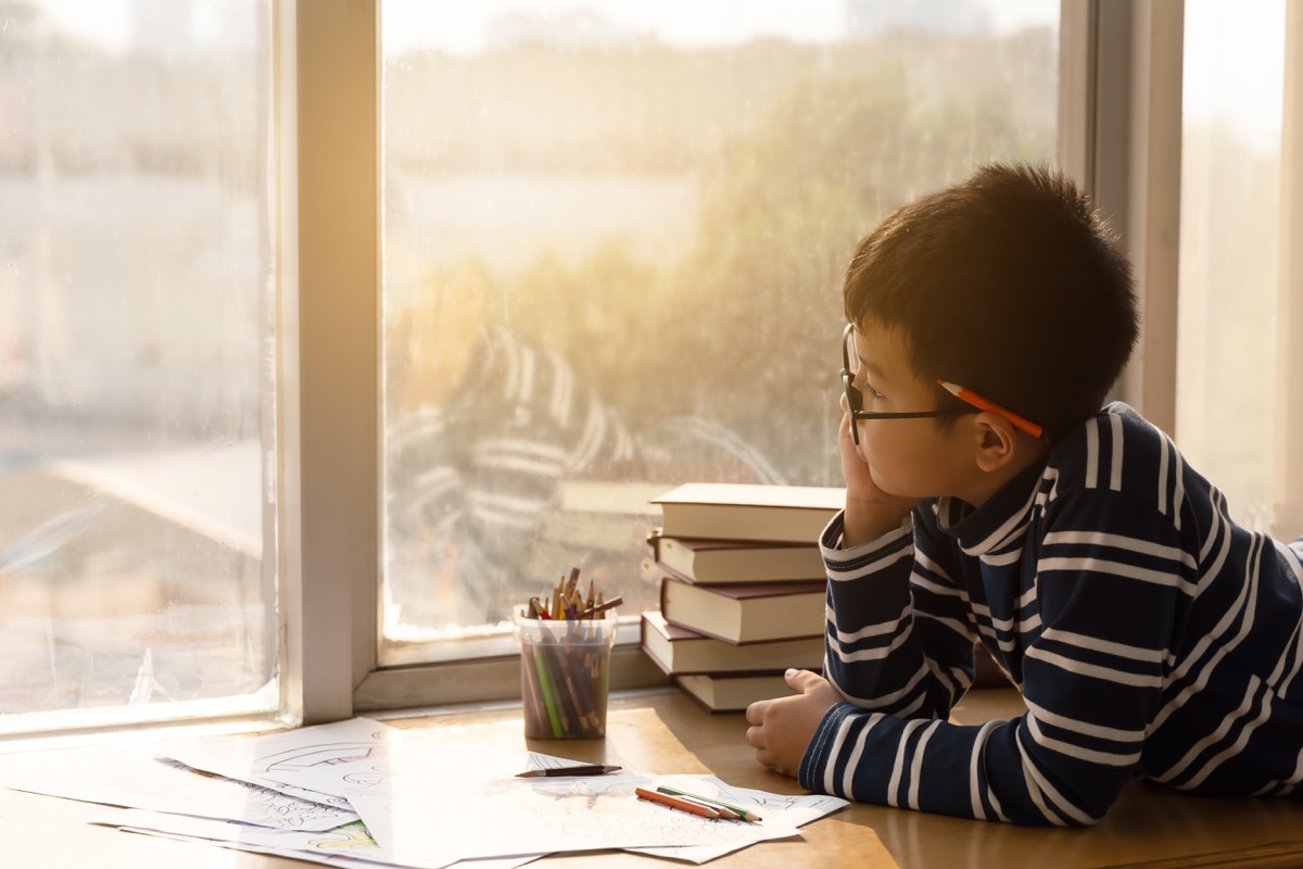 young asian boy looking out window