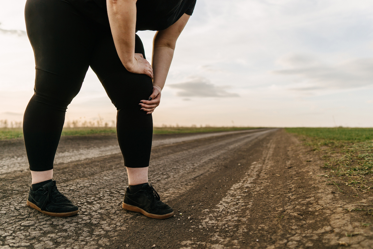 Overweight woman touching pain in leg