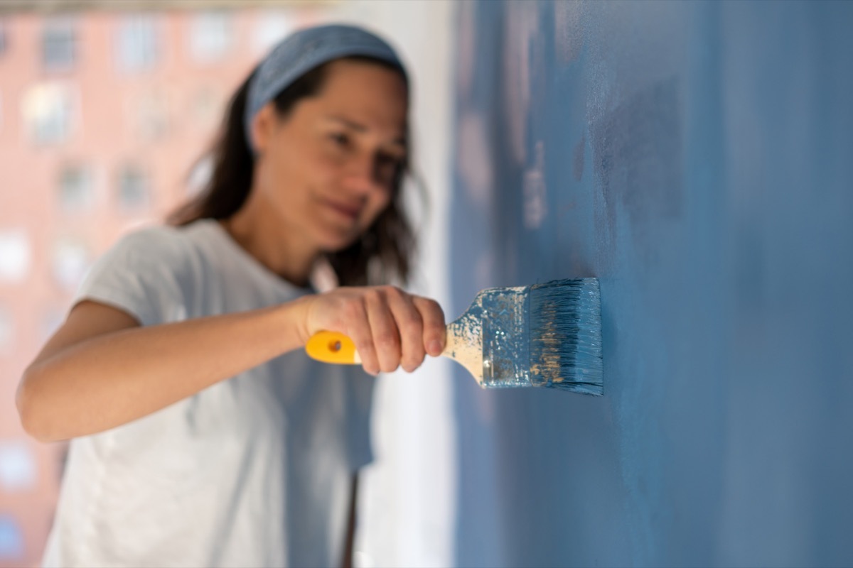 Close-up on a woman painting her house with focus on the brush – home improvement concepts