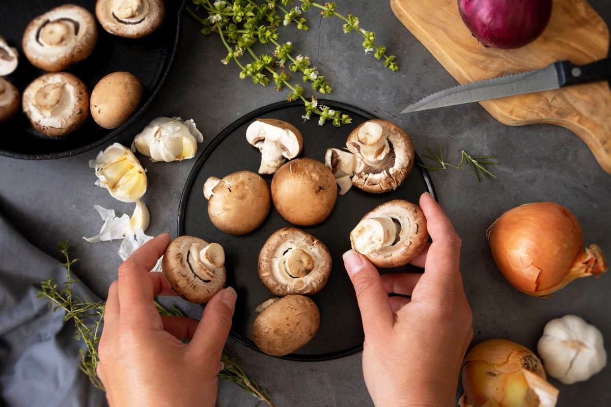 Cooking healthy food. Hands holding champignon mushrooms, flat lay.